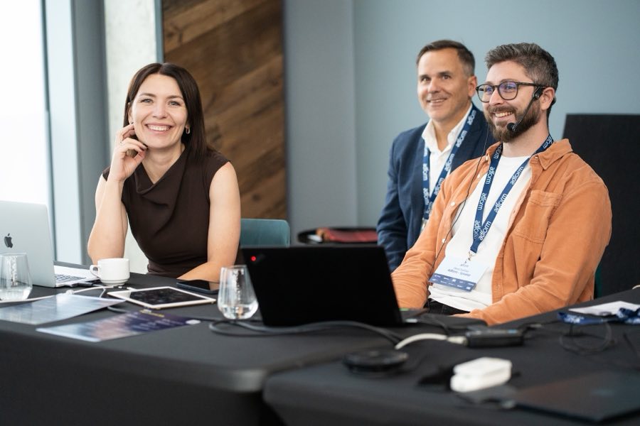 Usměvaví řečníci u stolu na konferenci Adform